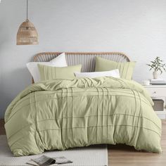 a bed with green comforter and pillows in a room