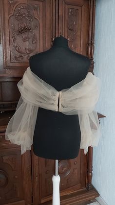 a mannequin with sheer fabric on it in front of a wooden cabinet and door