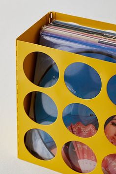 an open yellow box with photos inside on a white surface, containing magazines and cds