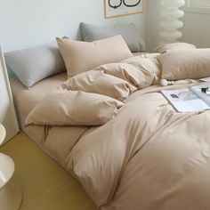 an unmade bed with beige sheets and pillows