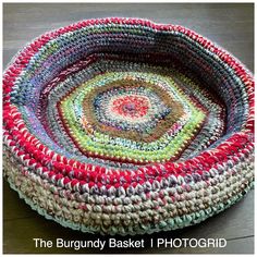 a crocheted basket sitting on top of a wooden floor next to a table