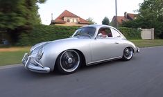 an old silver car driving down the street