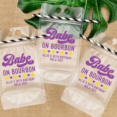 three bags with the words babe on bourbon are next to a plant and some paper straws