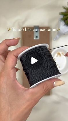 a hand holding a spool of black thread