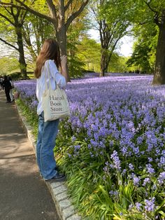 a woman taking a photo of purple flowers