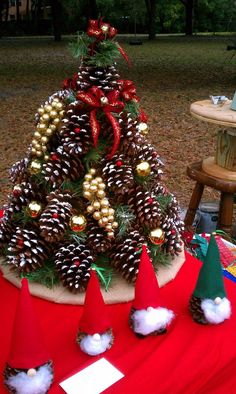 a christmas tree made out of pine cones and other decorations on a red table cloth