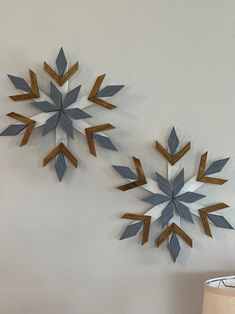 two metal snowflakes mounted to the wall next to a lamp on a table