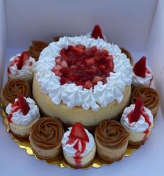 a heart shaped cake with strawberries on top in a white box next to cupcakes