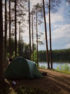 a tent pitched up in the woods next to a lake