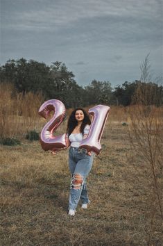 a woman standing in a field holding up the number twenty two balloons that spell out her name