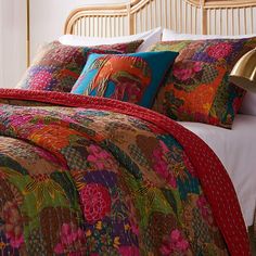 a bed with colorful comforters and pillows on it