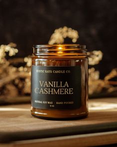 a jar of vanilla cashmere sits on a wooden table next to some gold flakes