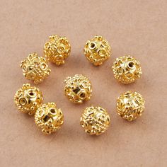 gold plated beads with holes in the middle on a brown surface, set against a beige background