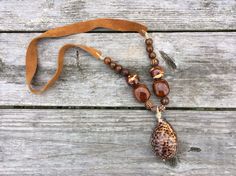 Nature made a seashell full of style!  The Tiger Cowry Shell is perfect for the animal print craze!  The ceramic beads come from the NC mountains.  This statement piece is so unique and perfect for your Fall outfits!  It is finished with tan suede for great comfort! Bohemian Brown Shell As Gift, Handmade Brown Bohemian Shell, Handmade Bohemian Brown Shell, Bohemian Brown Shell, Cowry Shell, Nc Mountains, Boho Glam, The Tiger, Tan Suede