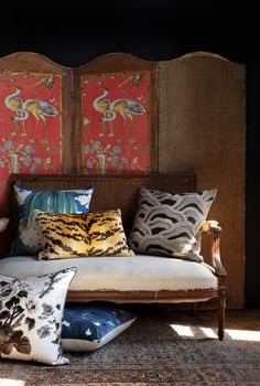 a bed with pillows on top of it in front of two colorful wall hangings