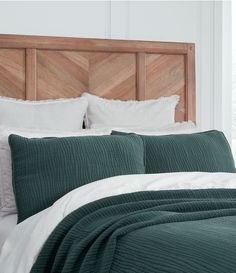 a bed with green bedspread and white pillows