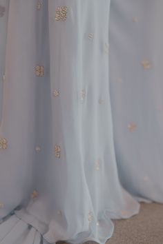 Dive into whimsical charm with our powder blue sharara set, featuring enchanting hand pearl work that dances across the ensemble. This set is your ticket to radiate ethereal beauty and capture hearts wherever you go. Kurta, pants, and dupatta included. Blue Sets With Pearl Embroidery For Reception, Elegant Light Blue Floor-length Sets, Light Blue Embellished Wedding Sets, Embellished Light Blue Wedding Sets, Light Blue Floor-length Sharara For Festive Occasions, Festive Blue Lehenga With Pearl Embroidery, Blue Sharara, Kurta Pants, Pearl Work