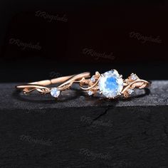 an oval blue topazte and diamond ring with leaves on it, sitting on a black surface