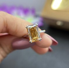 a woman's hand holding an engagement ring with a yellow diamond