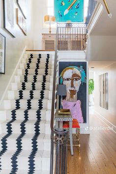 the stairs in this house are decorated with black and white geometric tiles, while an abstract painting is on the wall