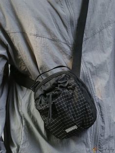 a person holding a small black bag on their back with one hand in the pocket