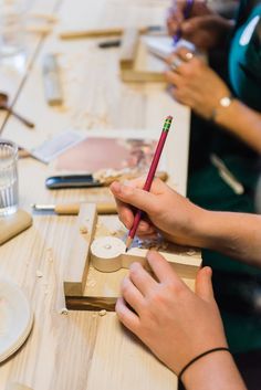 two people are working on crafts at a table