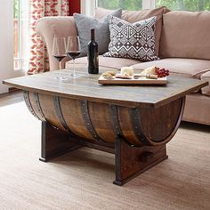 a living room filled with furniture and a wooden barrel table topped with wine glasses next to a window