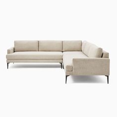 a large sectional couch sitting on top of a white floor next to a footstool