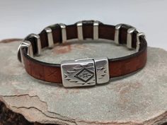 The Southwest Sunburst bracelet has 4 Southwest sliders that are on embossed leather with a Southwestern pattern. Magnetic clasp with an easy open thumbnail slot that stays put. The components are zinc plated with 99.9% sterling silver. Free of nickel, lead, cadmium. Hypoallergenic. The leather is 10mm in width. One size fits most. 8" Hand Tooled Adjustable Jewelry For Everyday, Southwestern Silver Leather Jewelry, Adjustable Southwestern Jewelry With Sterling Silver Clasp, Southwestern Style Brown Concho Bracelets, Southwestern Adjustable Nickel Free Bracelets, Adjustable Southwestern Hand-tooled Bracelets, Adjustable Sterling Silver Concho Bracelets, Rustic Hand-tooled Silver Jewelry, Rustic Adjustable Etched Jewelry