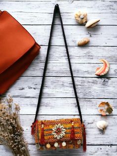 an orange purse sitting on top of a wooden table next to seashells and shells