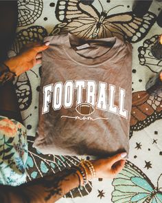 someone holding up a football t - shirt with the word football on it and butterflies in the background