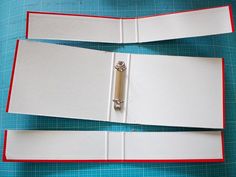 an open binder is sitting on top of a cutting mat with two pieces cut out