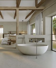 a large white bath tub sitting inside of a bathroom next to a bed and window