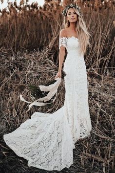 a woman wearing a white dress standing in tall grass