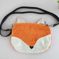 an orange and white purse with a fox face on it's front pocket, attached to a black strap