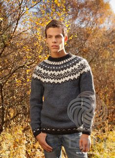 a man standing in the grass wearing a sweater