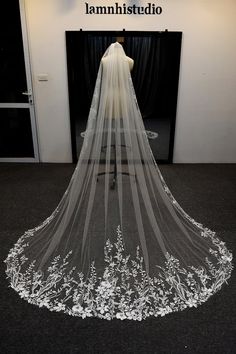 the back of a wedding veil with flowers and leaves on it in front of a black backdrop