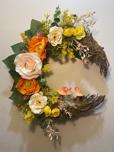 a floral wreath hanging on the wall with two little bird figurines in it