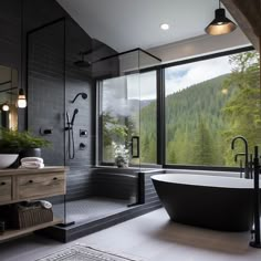 a black and white bathroom with a large tub in the middle, windows overlooking mountains