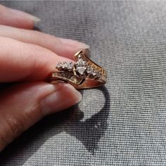 a woman's hand holding a gold ring with three diamonds