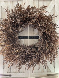 a wreath is hanging on the side of a wooden door with two black latches