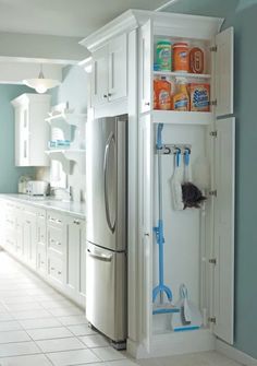 a kitchen with blue walls and white cabinets, including a refrigerator freezer that has cleaning supplies in it