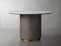 a round table with a white marble top and gold trim around the base, sitting on a grey surface