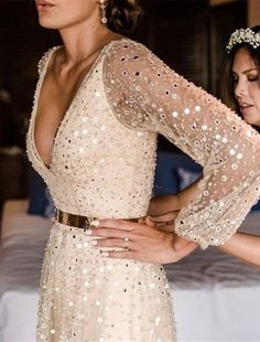 a woman in a wedding dress standing next to another woman wearing a tiara and holding her hand on her hip