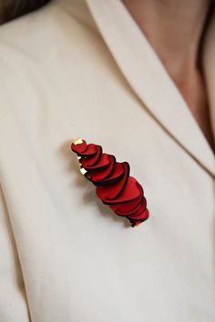 a woman wearing a white blazer with a red brooch on her lapel