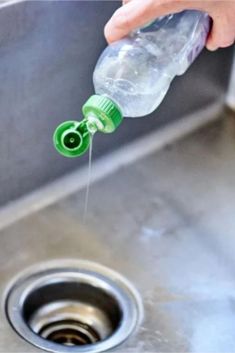 a person is pouring water into a sink with a green spigot in it