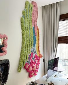 a desk with a laptop computer sitting on top of it next to a wall hanging