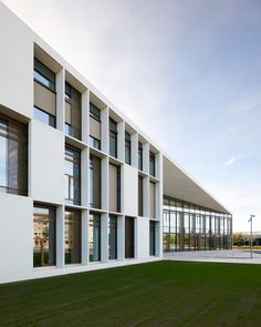 the building is white and has many windows on each side, along with green grass