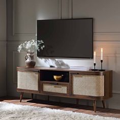 an entertainment center with a flat screen tv mounted on it's wall and wicker drawers