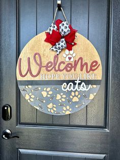 a welcome sign hanging on the front door of a house that says, welcome hope you'll like cats